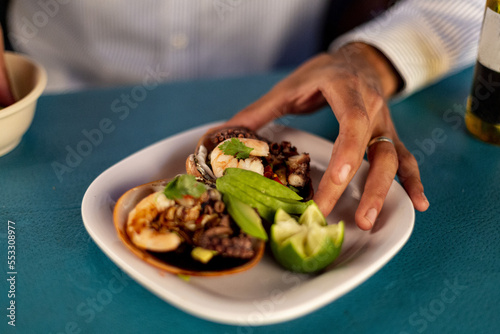 Tostada de pulpo con aguacate y salsa inglesa en un plato blanco.