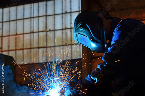 Workers wearing industrial uniforms and Welded Iron Mask at Steel welding plants, industrial safety first 