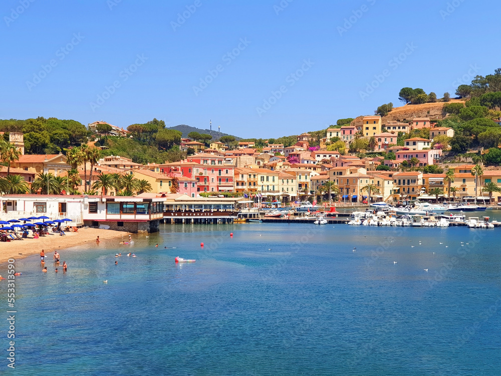 City of Porto Azzuro with colorful houses and tourists on the beach.