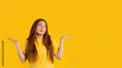 Confused pretty woman, shoulders up - can't help, makes gesture of I dont know. Difficult question, guilty reaction, puzzled stylish woman on yellow background. photo