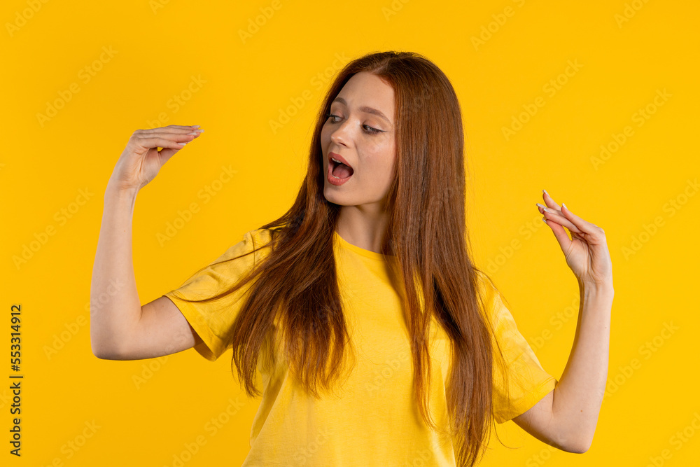 Irritated ginger woman showing bla-bla-bla gesture with hands, rolling eyes on yellow background. Empty promises, blah concept. Lier. Irritated ginger woman showing bla-bla-bla gesture with hands, rolling eyes on yellow background. Empty promises, blah concept. Lier.