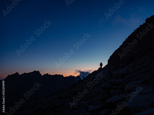 Silhouette of a mountaineer with a headlamp during sunset