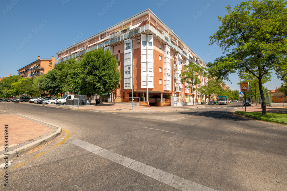 Facades of residential buildings with brick facades with white aluminum bay windows and a garage entrance from the street at a crossroads