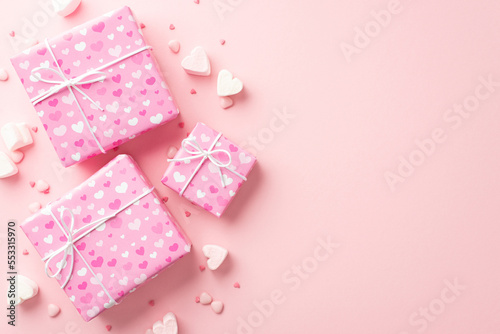 Valentine's Day concept. Top view photo of big present boxes heart shaped marshmallow and sprinkles on isolated pastel pink background with empty space © ActionGP