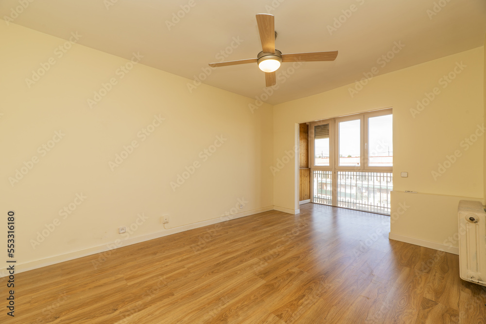 Obraz premium Empty living room with cream painted walls, glazed bay window with tongue and groove wood and four-blade ceiling fan