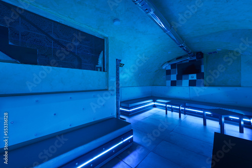 Entertainment room in an underground venue in a nightlife venue with rgb neon lighting and continuous white seating