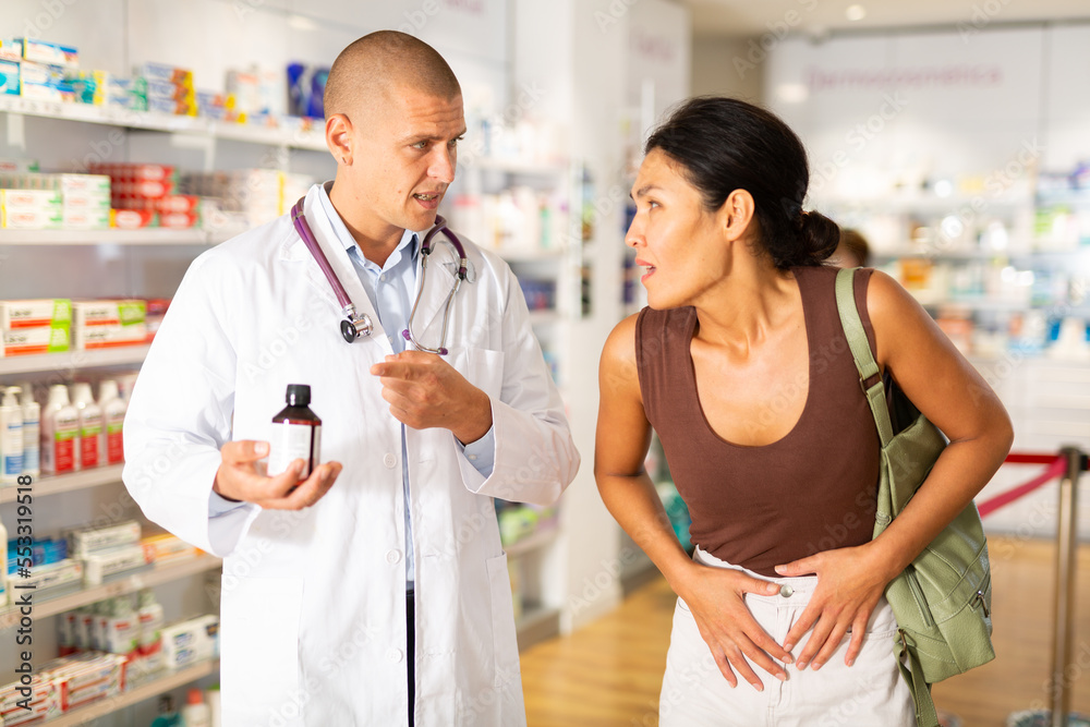 Woman complains to a pharmacist about a sore belly. Help in choosing a medicine in a pharmacy