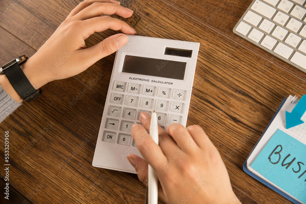 Businesswoman doing calculations in a calculator Businesswoman doing calculations in a calculator
