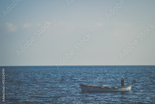 A lonely Fisherman in a small boat at the open blue sea on the coast of Naples, Italy  photo