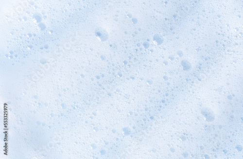 White foam texture with bubbles. Cosmetic soapy substance with bubbles. Creamy grainy macro backdrop. Cosmetic product foamy smudges and smears top view. White cleanser foam textured background.