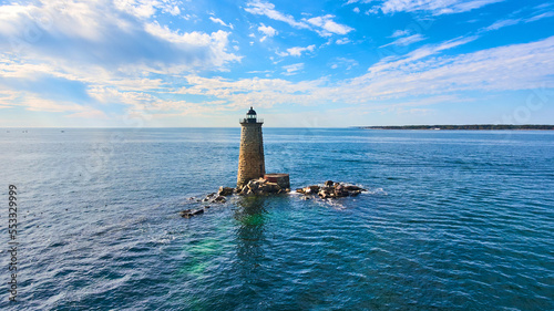 Lone stone lighthouse tower in middle of water with collapse rock rubble in Maine © Nicholas J. Klein
