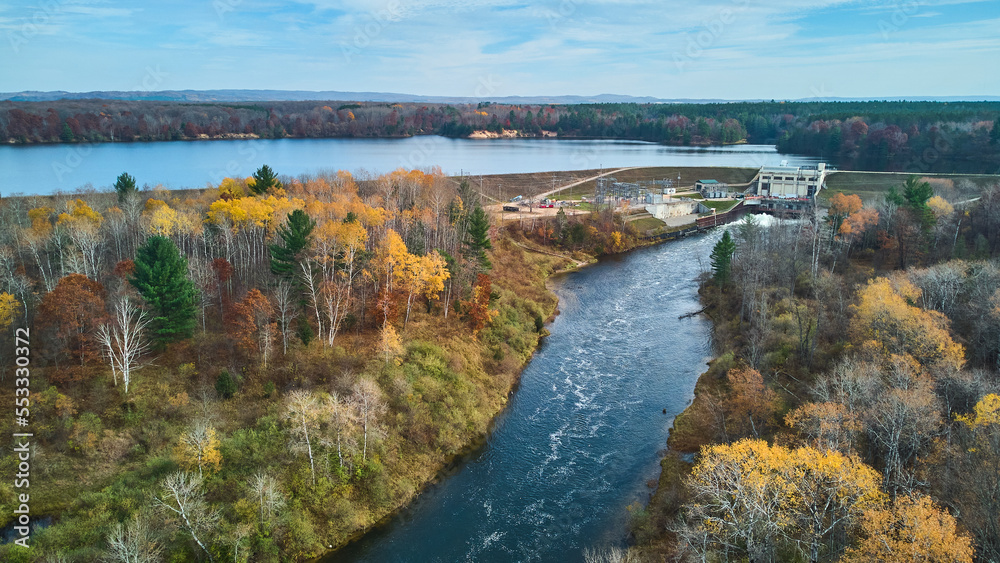 Muted fall colors in late fall aerial over Michigan river and lake with dam