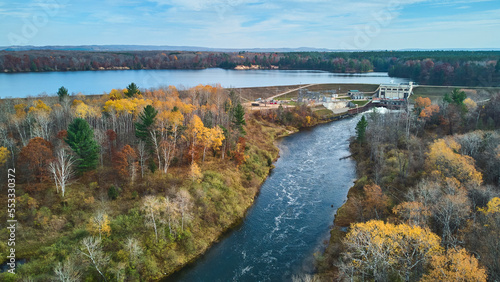 Muted fall colors in late fall aerial over Michigan river and lake with dam