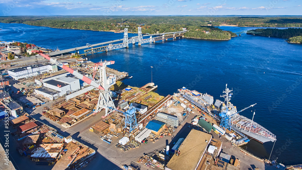 Huge shipyard on Maine river with lift bridge and ships under construction