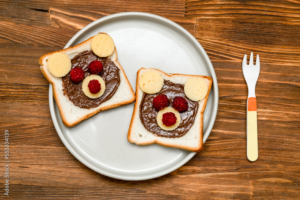 Funny bear face sandwich toast bread with peanut butter, cheese and raspberry on plate wooden background. Kids child sweet dessert breakfast lunch food close up Funny bear face sandwich toast bread with peanut butter, cheese and raspberry on plate wooden background. Kids child sweet dessert breakfast lunch food close up