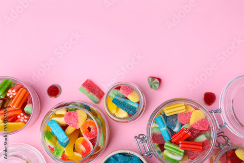 Tasty jelly candies in jars on orange background, flat lay. Space for text