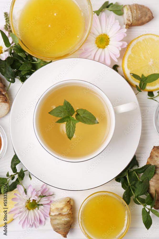 Flat lay composition with cup of delicious tea, honey and ginger on white wooden table Flat lay composition with cup of delicious tea, honey and ginger on white wooden table