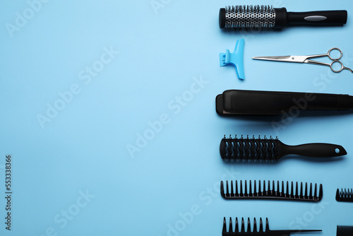 Flat lay composition of professional hairdresser tools on light blue background, space for text