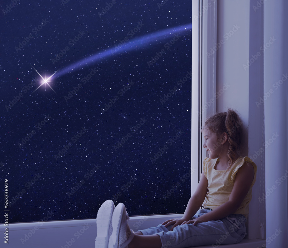 Cute little girl sitting on windowsill and looking at shooting star in ...
