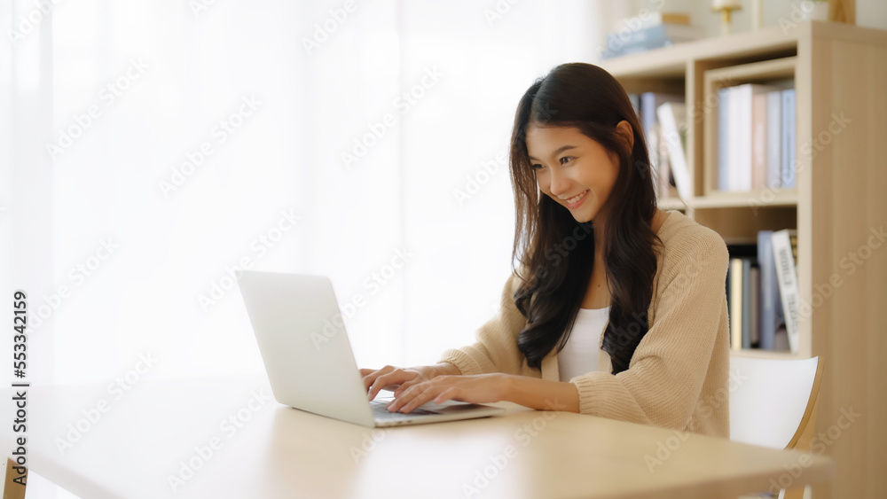 Young asian woman working at home. Female using computer laptop on desk at house Young asian woman working at home. Female using computer laptop on desk at house