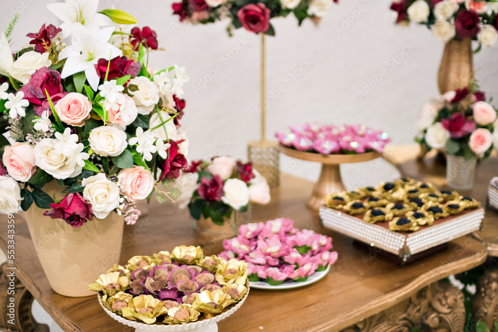 a tray with sweets and vases with red and white flowers on top of a table
