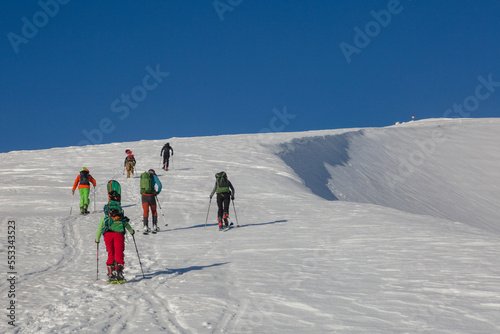 Group of skiers and snowboarders climbing up, teamwork