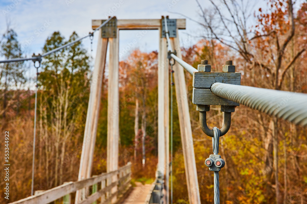 Detail of large thick support wires holding up suspension bridge by fall forest Detail of large thick support wires holding up suspension bridge by fall forest