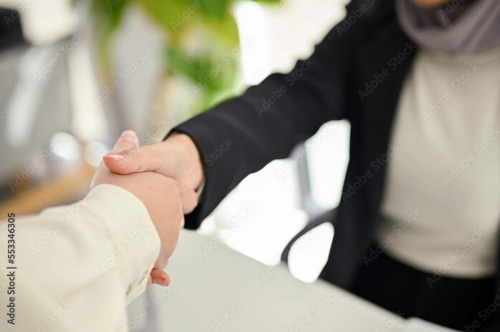 Close-up image of a Muslim businesswoman shaking hands with her business partner