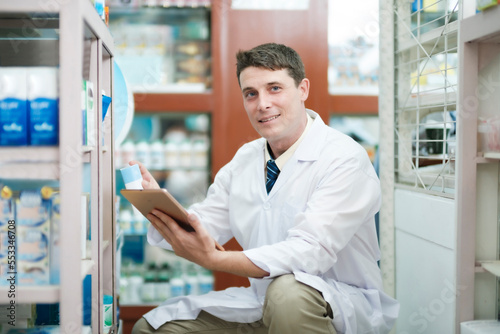 Male pharmacist checking stock inventory in pharmacy. © ijeab