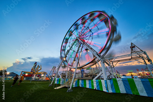 American county fair at dusk with blurred ferris wheel