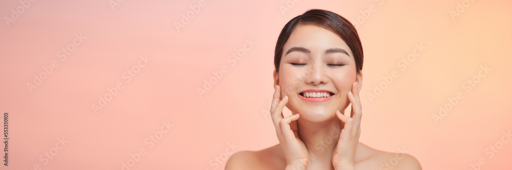 Beautiful face portrait of young woman is applying face cream on a cheek.