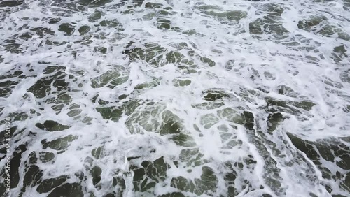 Surfer swimming towards large waves dives down under in time before waves crash down.