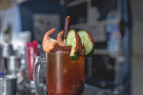 Deliciosa michelada preparada con pepino, camarón, chile chamoy, apio y clamato photo