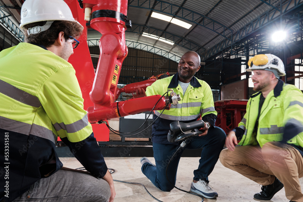 Male production engineers team discuss, test, and controls robotic arm in mechanical manufacturing factory, intelligent automatic machines in industrial business, and futuristic technology innovation. Male production engineers team discuss, test, and controls robotic arm in mechanical manufacturing factory, intelligent automatic machines in industrial business, and futuristic technology innovation.