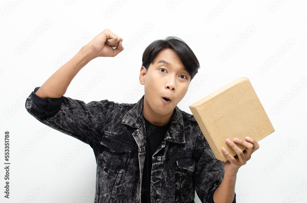 Young Asian man holding package over white background, smiling and excited. Concept of delivery courier and shipping services Young Asian man holding package over white background, smiling and excited. Concept of delivery courier and shipping services