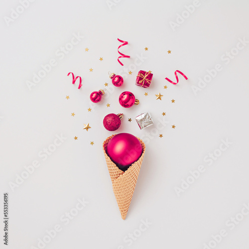 Creative Christmas concept made with New Years decoration baubles in ice cream cone and ornament decoration on white background . Minimal concept of Christmas and New Year holiday style. Flat lay.
