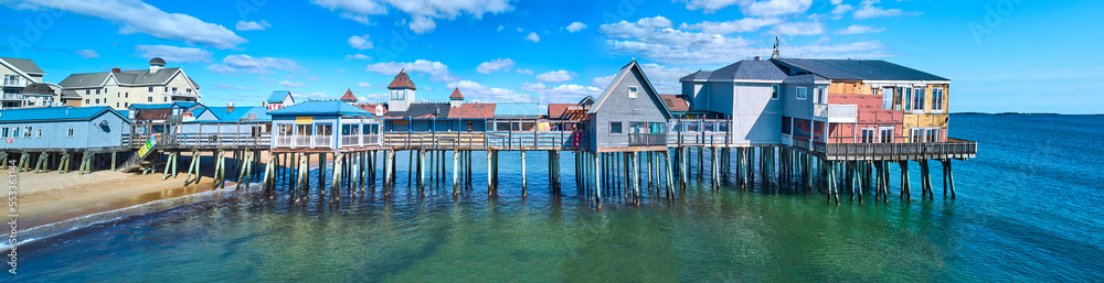 Stunning side profile of entire old wood pier in Maine covered in shops and buildings on beach Stunning side profile of entire old wood pier in Maine covered in shops and buildings on beach