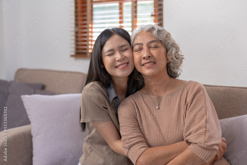 Asian mother and daughter spend the holidays in their living room, expressing their love by embracing each other at home happily and warmly. Asian mother and daughter spend the holidays in their living room, expressing their love by embracing each other at home happily and warmly.