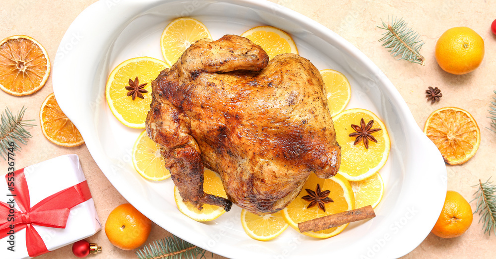 Baking dish with tasty roasted chicken, orange slices and Christmas gift on grunge background Baking dish with tasty roasted chicken, orange slices and Christmas gift on grunge background