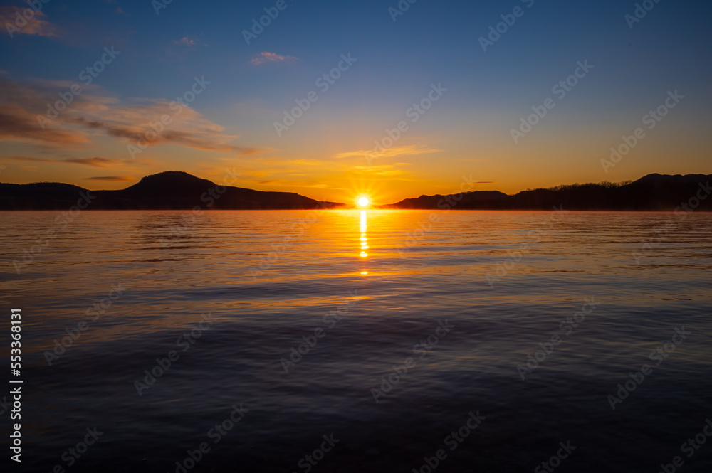 朝陽の昇る夜明けの湖。日本の北海道の屈斜路湖。 朝陽の昇る夜明けの湖。日本の北海道の屈斜路湖。