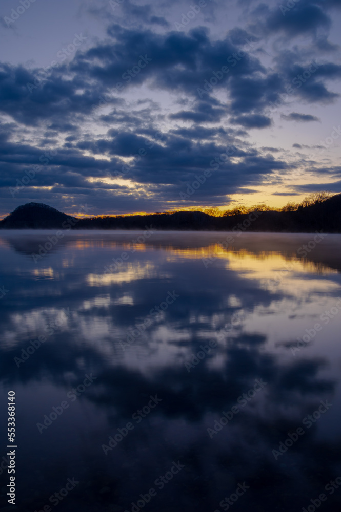 夜明けの湖の水面に反射する空。日本の北海道の屈斜路湖。