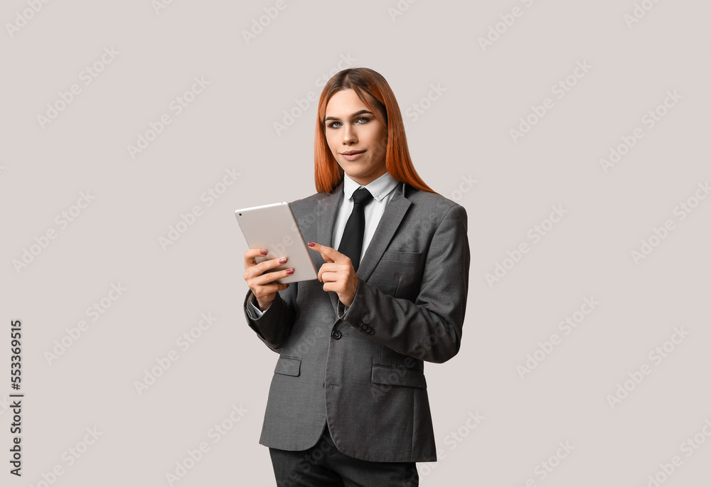 Beautiful transgender secretary with tablet computer on grey background Beautiful transgender secretary with tablet computer on grey background