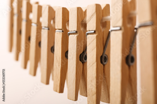 Wooden clothespins hanging on clothesline against color background, closeup