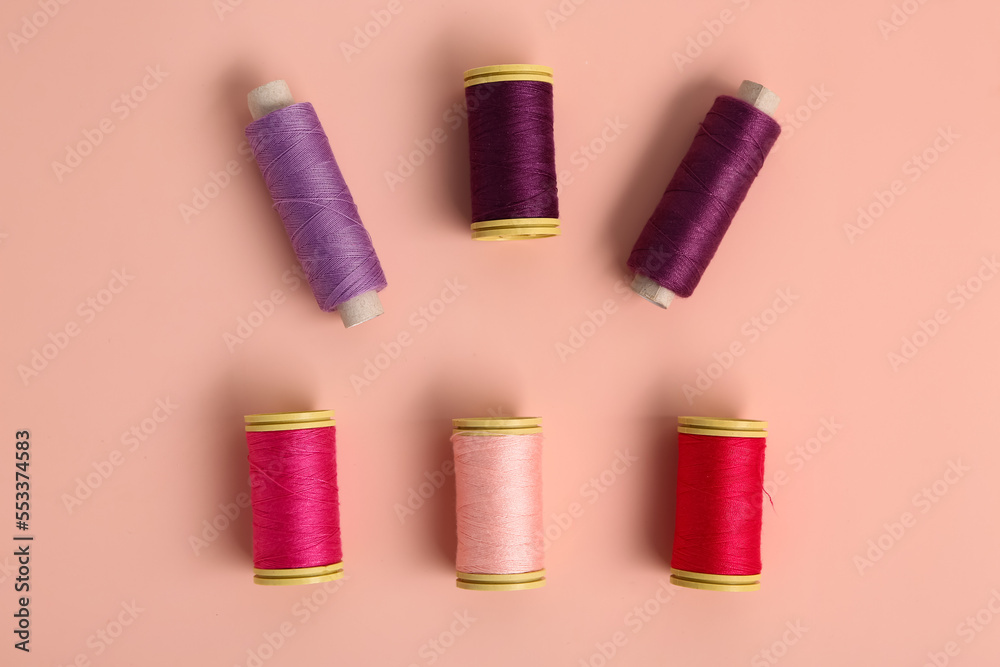 Colorful thread spools on pink background Colorful thread spools on pink background