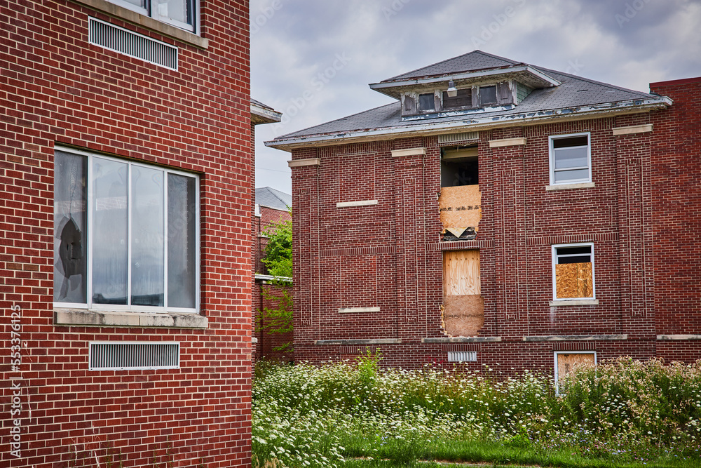 Abandoned brick buildings in fields with boarded up windows Abandoned brick buildings in fields with boarded up windows