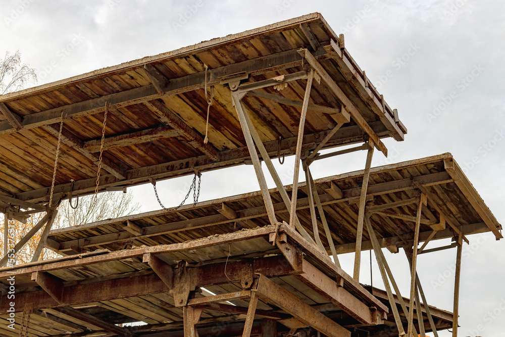 Reinforced scaffolding for the work of masons in the construction of brick walls. Apparel for work on the construction site and storage of materials. Close-up. Construction of brick walls.