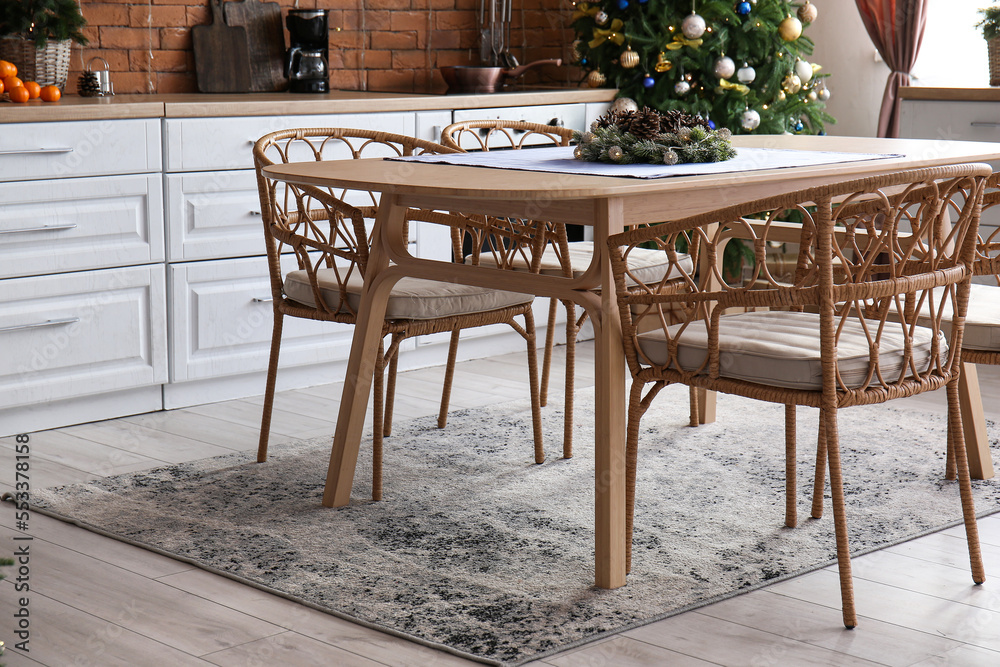 Dining table with Christmas branches and fir cones in kitchen