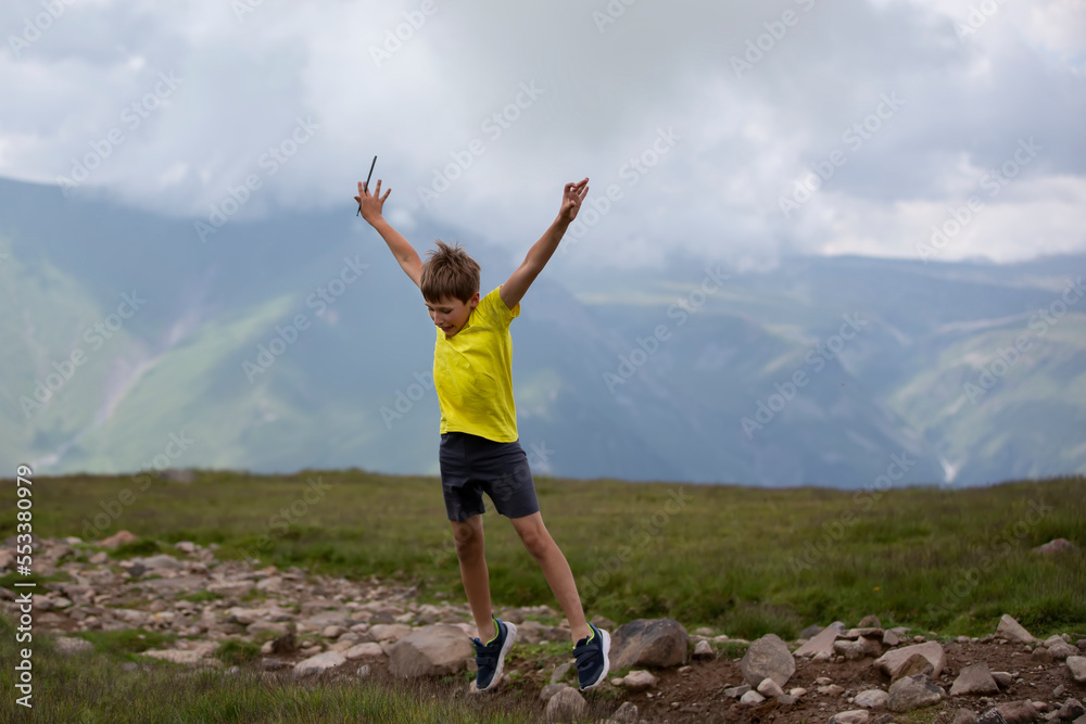Happy boy against the backdrop of a mountain landscape, joyfully jumping, enjoying life. Happy boy against the backdrop of a mountain landscape, joyfully jumping, enjoying life.
