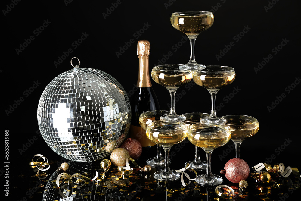 Obraz premium Glasses of champagne, bottle, Christmas balls and serpentine on black background