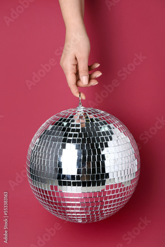 Woman with disco ball on red background